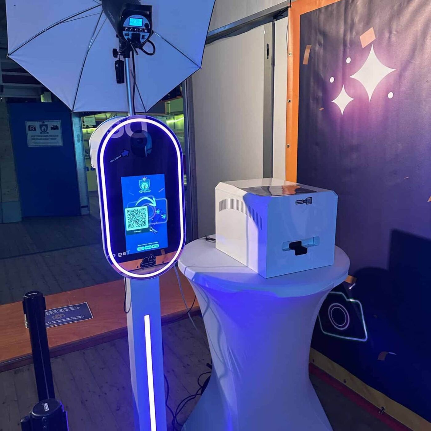Ovale photobooth met paarse LED-ring naast een statafel met printer